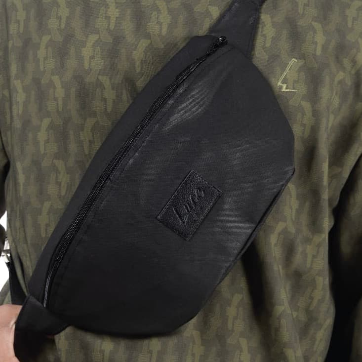 lucewear: homme portant un grand sac banane noir enduit
